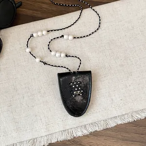 Detailopname van vintage leren hanger ketting met parels en een stippellijntje.