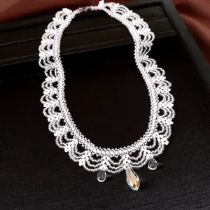 Detail van handgemaakte witte kralen kanten ketting met heldere kristallen druppels