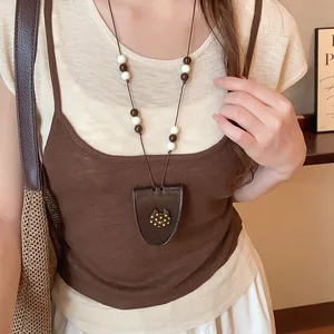 Retro lederen hanger ketting met kattenbedeltje gedragen met een bruine gebreide top.