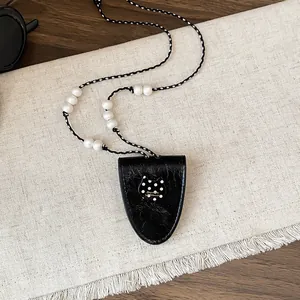 Gedetailleerd overzicht van vintage zwart leren brillenclipketting met luxe parelkralen