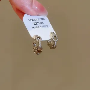 Détail macro de boucles d'oreilles créoles torsadées en argent avec strass brillants