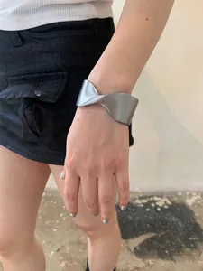 Close-up view of a minimalist chunky silver twisted cuff bracelet worn by a female model