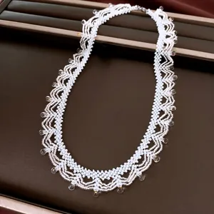 Detail van handgemaakte witte glazen kralenketting met elegant geschulpt patroon