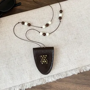 Macro-opname van retro bruin leren beren hanger met een mooie kralen ketting