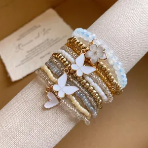 Böhmisches Perlenarmband-Set mit weißen Schmetterlings- und Blumenanhängern in der Nahaufnahme.