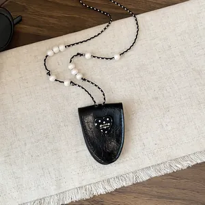 Gedetailleerd beeld van de zwarte lederen hart hanger en de witte kralen halsketting