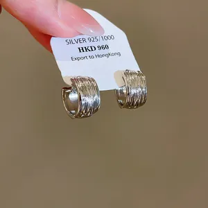 Vue détaillée de créoles en forme de C en argent 925 texturé sur un support blanc
