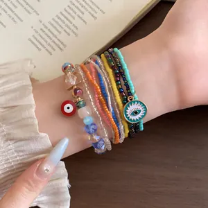 Nahaufnahme von buntem Boho-Perlenarmband-Set mit Evil-Eye-Anhängern am Handgelenk.