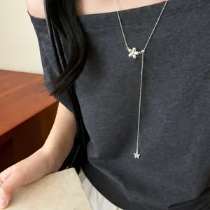 Macro view of an elegant silver flower pendant Y-shaped necklace worn by a model
