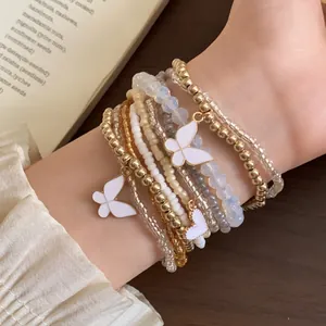 Detail eines mehrschichtigen Boho-Perlenarmband-Sets mit Schmetterlings- und Herzanhängern