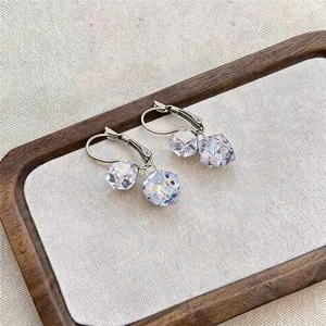 Detail shot of French style earrings with clear crystal cube pendants in a wooden tray