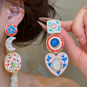 Detailopname van vintage asymmetrische emaille oorbellen met bloemen- en hartpatronen