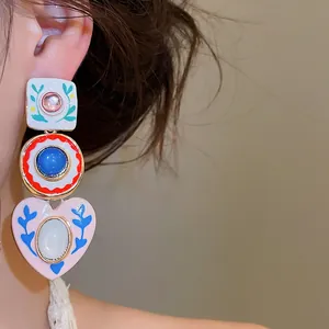 Detailopname van vintage kleurrijke emaille oorbellen met bloemen- en hartpatronen