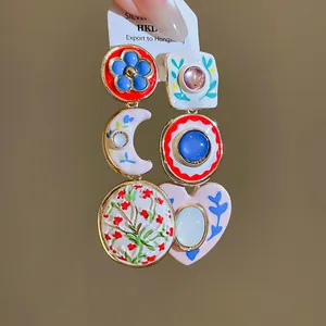 Detailopname van vintage asymmetrische oorbellen met kleurrijke bloemen- en maanpatronen