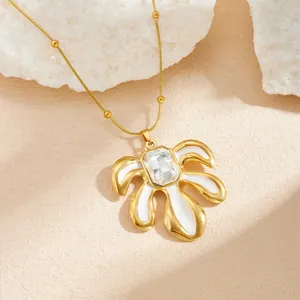 Gros plan d'un collier feuille plaqué or avec émail blanc et détails en zircone.