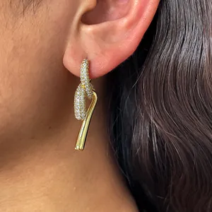 Gros plan de boucles d'oreilles nœud plaquées or 18 carats avec zircons sur une oreille