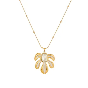 Vue détaillée d'un collier pendentif feuille doré avec un centre en cristal.