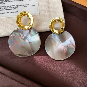 Macro view of vintage geometric round stud earrings with hammered gold and iridescent acetate
