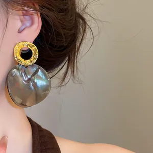 Close-up of vintage geometric acetate round earrings with golden hammered metal detail