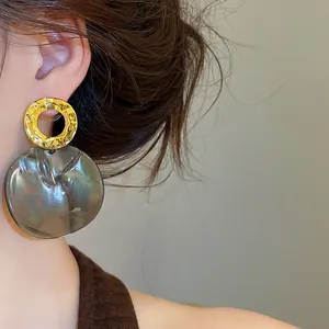 Close-up of vintage geometric round acetate earrings on a model with gold hammered details