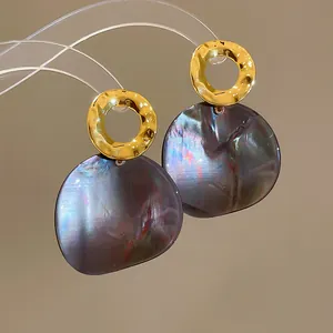 Macro shot of vintage gold rings and iridescent dark acetate drops on stud earrings