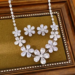 Detailansicht von elegantem Zirkon-Blumen-Halsketten- und Ohrring-Set auf braunem Stoff