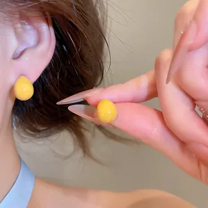 Nahaufnahme der gelben Emaille-Ohrstecker in Tropfenform mit glänzendem Finish