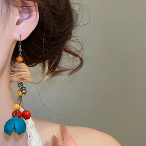 Detail of a vintage ethnic wooden tassel earring with blue floral drop on a model