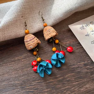 Macro view of vintage ethnic style earrings featuring wooden bells and blue floral tassels