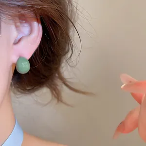 Detaillierte Nahaufnahme eines Models mit minimalistischen grünen Wassertropfen-Ohrsteckern.