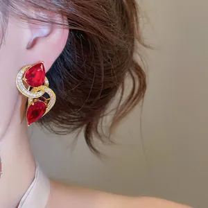 Detail van elegante gouden oorbellen met rode zirkoonstenen op een Aziatisch model