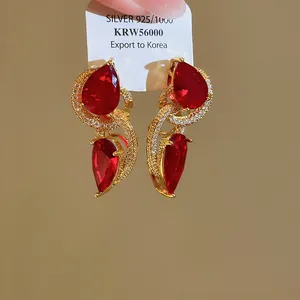 Detail van 18k vergulde oorbellen met luxueuze rode druppelvormige zirkonia en gouden afwerking.