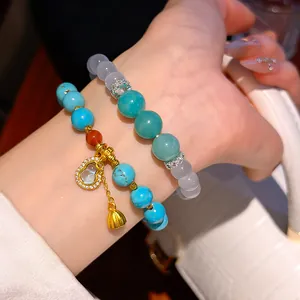 Detail of two beaded hulu bracelets with turquoise and aqua resin beads on wrist.