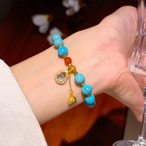 Close-up of a turquoise beaded bracelet with a stone-inlaid gourd and gold charms