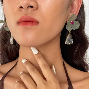 Gros plan de boucles d'oreilles fleur en acrylique vert et pendentif en cristal.