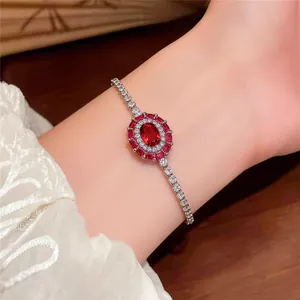 Detailed view of a French luxury oval red zircon bracelet with halo design on wrist