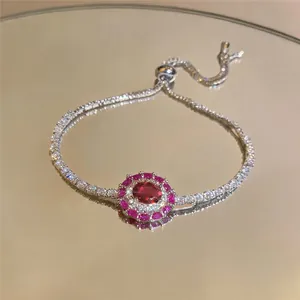 Close-up detail of an adjustable zircon bracelet with a red oval gemstone halo