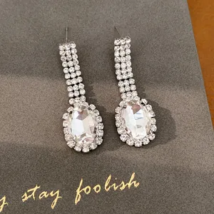 Detaillierte Makroaufnahme eleganter ovaler Strass-Ohrhänger auf einer dunkelgrauen Karte
