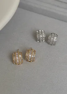 Detailansicht von funkelnden Zirkonia-Halbbogenohrsteckern in Silber- und Goldtönen.