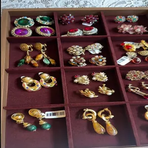 Sammlung verschiedener Vintage-Ohrringe mit Strass und Perlen in einer braunen Samtschale.