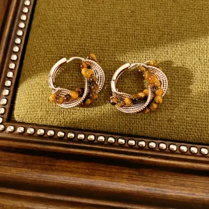 Detailed macro view of vintage tiger eye beaded hoop earrings with twisted metal design