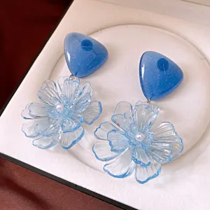 Detailansicht von blauen, lichtdurchlässigen Blumenohrringen mit Herz-Top in einer Box