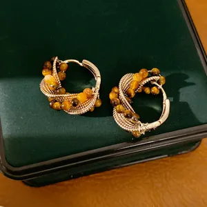 Close-up of vintage gold hoop earrings with tiger eye beads on a green box