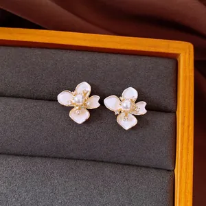 Detailaufnahme von eleganten weißen Emaille-Blumenohrsteckern mit Perle in einer Box