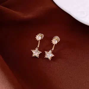 Nahaufnahme eleganter goldener sternförmiger Strass-Ohrringe auf braunem Stoff