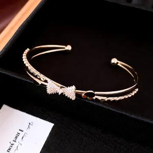 Detailansicht eines eleganten, zweilagigen Goldarmbands mit glitzernder Zirkonia-Schleife