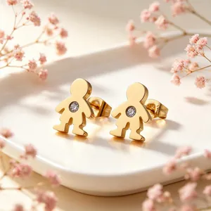 Gros plan de boucles d'oreilles en acier titane doré en forme de petit personnage poli.