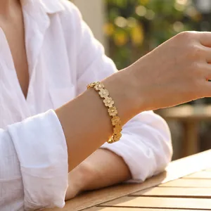 Detailopname van vintage 18k vergulde roestvrijstalen madeliefje schakelarmband op een vrouwenpols