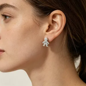 Vue détaillée d'une boucle d'oreille garçon en acier argenté portée sur le lobe d'une femme