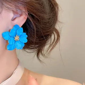 Detailopname van een matte blauwe bloemoorbel met een gouden hartje bij een model